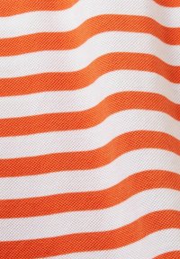 Tissu présentant des bandes ondulées alternées en orange vif et blanc. Le tissu a une surface texturée et un aspect doux et tissé.