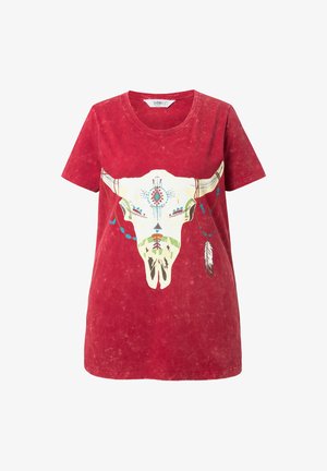 Camiseta de algodón roja con un corte relajado, que presenta un gráfico central de un cráneo de toro adornado con cuentas y plumas en verde y azul.
