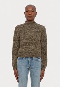 Pull en col roulé en tricot avec un motif étoilé brun et noir ; design ajusté avec des poignets et un ourlet côtelés, associé à un jean bleu clair.