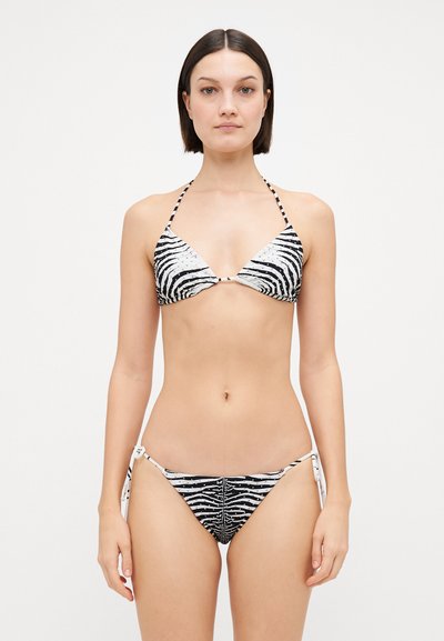 Bikini s potiskem zebry v černé a bílé. Halter top s trojúhelníkovými košíčky; kalhotky na zavazování po stranách s možností nastavení. Hladká tkanina, minimální kovové doplňky.