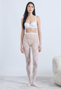 Διαφανείς, ανοιχτό μπεζ καλσόν με περίτεχνο λευκό δαντελένιο σχέδιο, σε συνδυασμό με απλό λευκό σουτιέν. Ομαλή υφή και άψογη εφαρμογή.