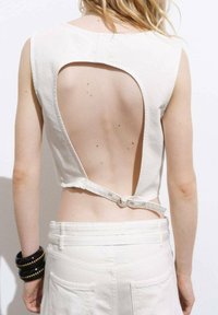 Weißes ärmelloses Oberteil mit einem großen Ausschnitt am Rücken, der mit einem Riemen und einer Schnalle gesichert ist, aus weichem Baumwollstoff mit glatter Textur.