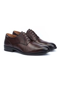 Bruine leren dresschoenen met een glanzende afwerking, ronde neus en vetersluiting. Beschikt over een lichte hak en minimale stikselaccenten.