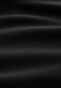 Tela negra lisa con pliegues sutiles y textura suave, mostrando una vista de cerca del detalle de la superficie del material.