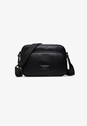 Sac bandoulière en cuir noir avec sangle ajustable, poche zippée à l'avant et forme rectangulaire sur fond blanc.