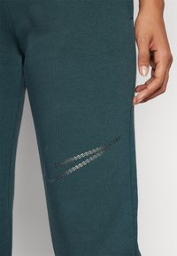 Nike Sportswear CLUB SHINE PANTS - Teplákové kalhoty - deep jungle