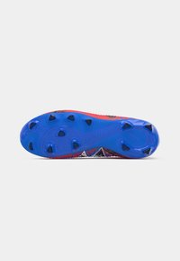 Crampons de football rouges et noirs avec une semelle texturée bleue, comportant des pointes noires et un dessus à motifs pour la traction et l'adhérence.