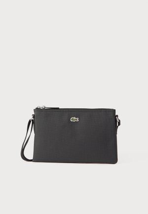 Bolsa de mão preta feita de material sintético texturizado. Apresenta um fecho com zip e um pequeno logótipo verde na parte da frente. Inclui uma alça para o pulso.