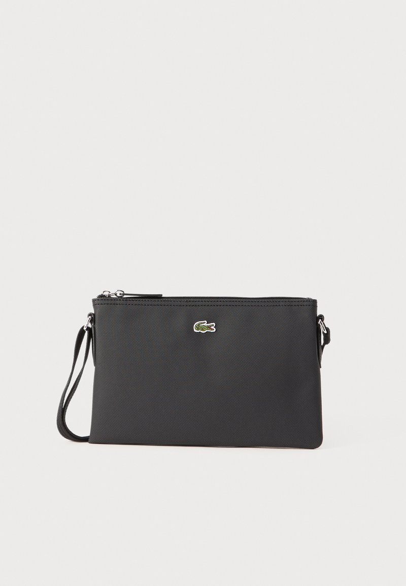Borse da polso nera realizzata in materiale sintetico texturizzato. Presenta una chiusura con zip e un piccolo logo verde sulla parte anteriore. Include una tracolla.