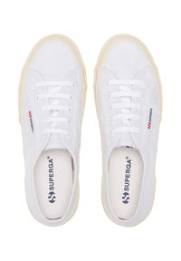Sneakers bianchi in tela con superficie testurizzata, punta tonda e stringhe coordinate. Suola in gomma color crema con logo del marchio sul lato e sulla soletta.