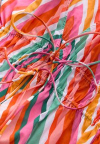 Abito multicolore con strisce oblique in rosa, arancione, verde e bianco. Presenta una vita elastica arricciata e lacci regolabili.