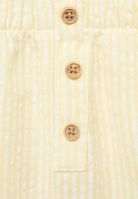 Tissu rayé jaune et blanc avec une finition texturée. Comprend trois boutons en bois avec quatre trous chacun, espacés uniformément le long du centre.