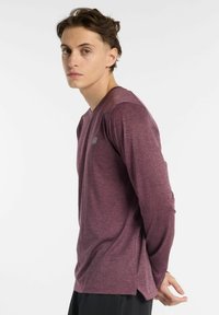 Long-sleeve athletic shirt in a maroon heathered fabric, featuring a subtle logo on the chest and side slits at the hem for ease of movement.