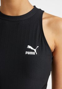 Top negro sin mangas con textura acanalada, que presenta un logo blanco de Puma en el pecho. Cuello alto y diseño ajustado.