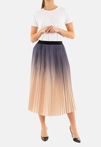 Falda midi plisada que presenta un degradado de azul oscuro en la parte superior a durazno claro en la parte inferior, con una cinturilla elástica negra. Combinada con una camiseta blanca.