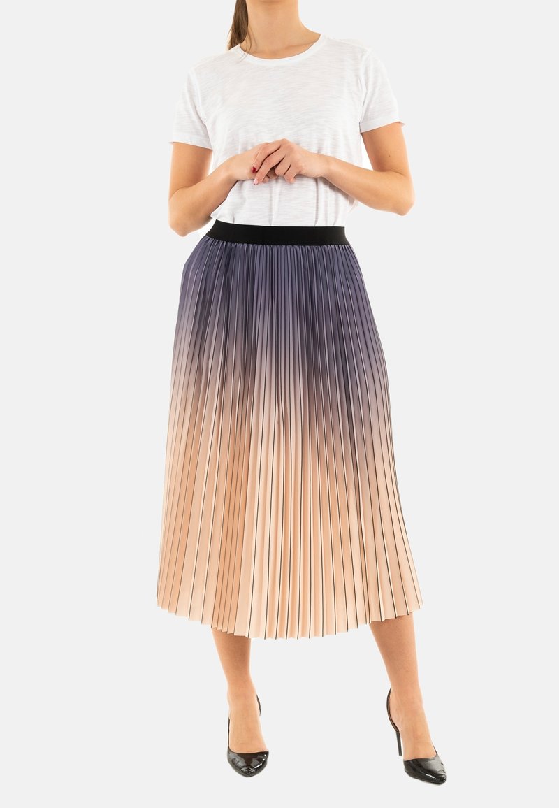 Falda midi plisada que presenta un degradado de azul oscuro en la parte superior a durazno claro en la parte inferior, con una cinturilla elástica negra. Combinada con una camiseta blanca.