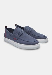 Pantofi slip-on din pânză albastră marină, cu talpă din cauciuc albă, având o textură netedă, accente cusute și un design cu vârf rotunjit.