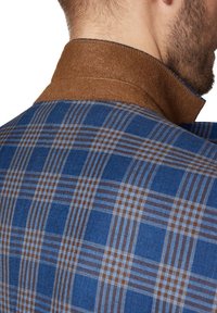 Niebieska tkanina w kratę z brązowymi akcentami na wyraźnym kołnierzu, prezentująca strukturę przypominającą wełnę z wyraźnymi wzorami w kratkę.