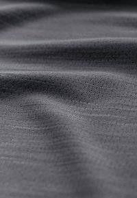 Grey textured fabric with a subtle pattern of small dots, folded and draped to show its soft, smooth surface and flexibility.