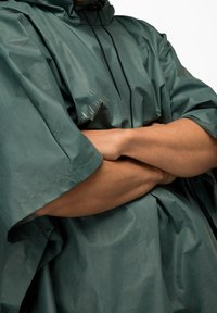 Vandtæt poncho i mørkegrøn, med hætte, justerbar snor og brede ærmer. Fremstillet af letvægtigt, struktureret materiale.
