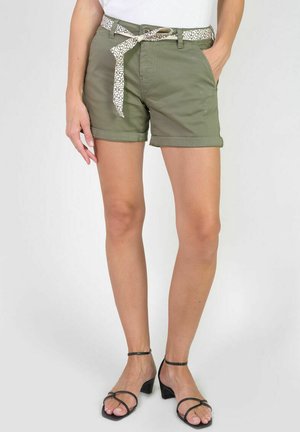 Shorts en coton vert olive avec des ourlets retroussés, dotés d'une ceinture à motifs blancs, de poches avant et d'une coupe ajustée. Associés à des talons noirs à brides.