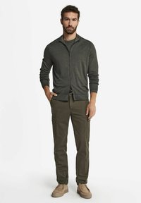 Szary kardigan na zamek, oliwkowe spodnie cargo, beżowe buty. Kardigan ma gładką strukturę, podczas gdy spodnie mają kieszenie użytkowe.