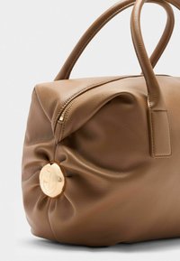 Borsa a mano in pelle marrone con forma arrotondata, chiusura con zip e un logo metallico centrale. Superficie texturizzata con sottili dettagli plissettati.