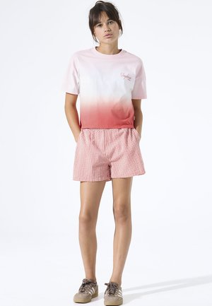 Camiseta de algodón con un degradado de rosa a rojo y logo bordado, combinada con pantalones cortos de cuadros vichy rojos y blancos con cintura elástica.