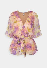 Blouse transparente à motifs floraux violets, roses et jaunes, manches courtes évasées, col en V et ceinture nouée à la taille sur fond blanc.