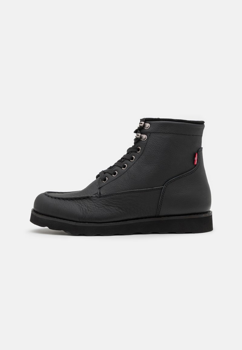 Bottines en cuir noir, avec un bout rond, un design à lacets et une surface texturée. Elles présentent des œillets en métal et une semelle noire robuste.