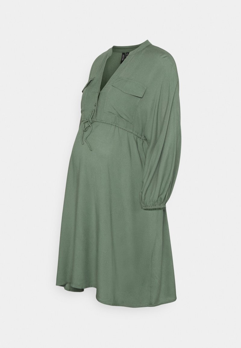 Vestido de maternidade em verde sálvia, com decote em V, dois bolsos no peito, cintura com cordão ajustável e mangas longas bufantes. Feito de tecido leve.