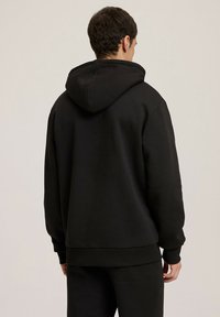 Czarna bluza z kapturem o luźnym kroju, z przednią kieszenią typu kangur, ściągaczami na rękawach i dole. Materiał wydaje się gładki z minimalnymi detalami.