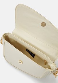 Bolso bandolera de cuero crema con textura suave, herrajes dorados y cierre magnético. El interior cuenta con un bolsillo con cremallera y forro beige.