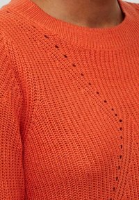 Gestrickter oranger Pullover mit rundem Ausschnitt. Verfügt über strukturierte Maschen und durchbrochene Details entlang der Schulter und Brust.