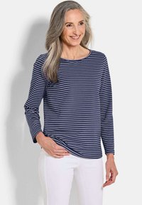 Marineblaues Langarmoberteil mit weißen Streifen, Rundhalsausschnitt und lockerer Passform, kombiniert mit weißen Hosen. Glattes Baumwollmaterial.