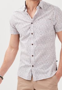 Short-sleeve button-up shirt in white with a herringbone pattern in blue and red, featuring brown buttons and a pointed collar.
