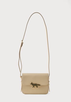 Sac bandoulière en cuir beige avec sangle réglable et fermoir doré en forme de renard sur le rabat avant.