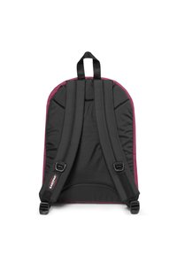 Svart tygryggsäck med maroon-kant, med justerbara vadderade axelremmar och ett handtag i toppen. Enkel, funktionell design.