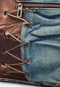 Torba tekstylna z nadrukiem imitującym dżins, z luźnymi sznurówkami i zamkiem błyskawicznym. Wykonana z dżinsu i tkaniny, z kontrastującymi kolorami niebieskim i brązowym.