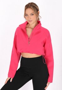 Giacca cropped aderente di un vivace rosa, con colletto alto, chiusura con zip e orlo arricciato. Tessuto liscio con maniche lunghe.