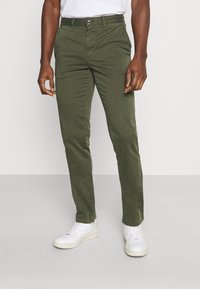 Groene katoen chino's met een slim-fit ontwerp, voorzien van een knoopsluiting en zijzakken, in combinatie met witte sneakers. Soepele textuur.
