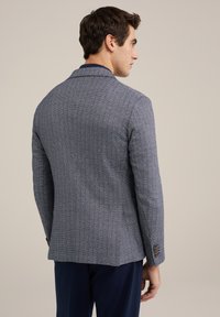 Marineblauwe blazer met visgraatpatroon, met notch revers, twee knopen en een gestructureerde stof. Heeft een getailleerde pasvorm en contrasterende stikseldetails.