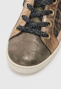 Metallisch bronze Sneaker mit strukturiertem, metallischem Zehenkappen, schwarzen und silbernen gesprenkelten Schnürsenkeln und einem Leopardenmuster an der Seitenpartie. Weiße Gummisohle.