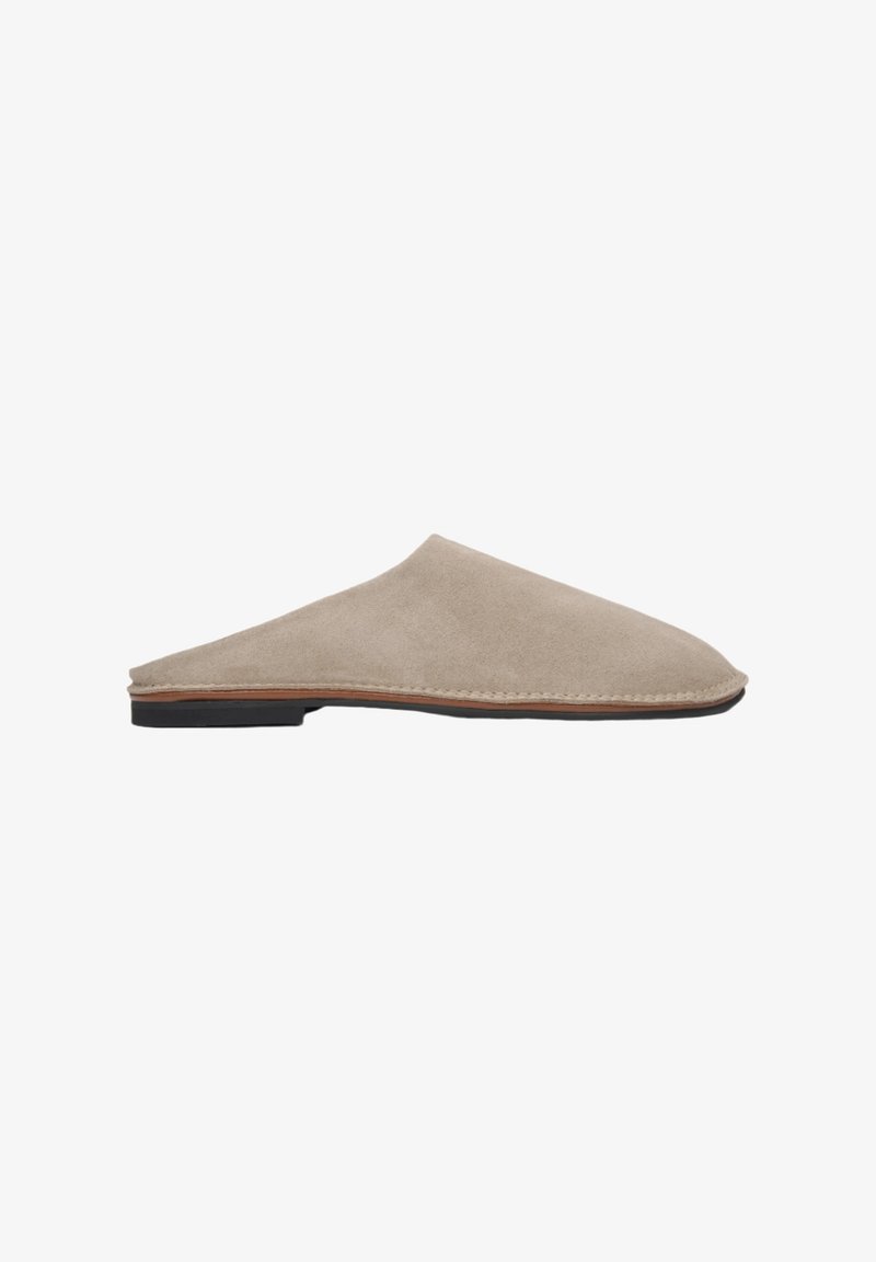 Beige suède instappers met een gladde textuur, ronde neus en een dunne bruine leren middenzool. Vlakke zwarte rubberen zool.