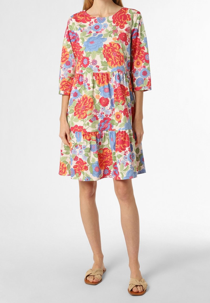 Floral dress with three-quarter sleeves, tiered design, colorful large flowers in red, blue, and green, made of lightweight fabric, paired with tan sandals.