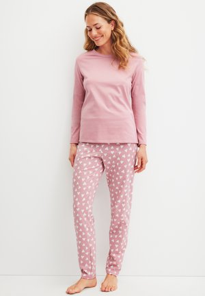 Maglietta a maniche lunghe di un rosa chiaro abbinata a pantaloni da pigiama rosa con un motivo a cuori bianchi. Tessuto liscio, design aderente e taglio alla caviglia.