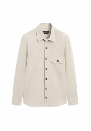 Lys beige langærmet skjorte med krave, sorte knapper foran og på klappen af venstre brystlomme, vist på hvid baggrund.