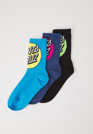Drie paar sokken: één in turquoise, één in marineblauw en één in zwart. Elk paar heeft een cirkelvormig "SANTA CRUZ" logo in geel, roze en groen.
