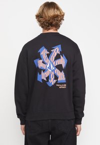 Sudadera negra de manga larga con un diseño geométrico colorido en la parte posterior, que incluye flechas azules y un patrón naranja.