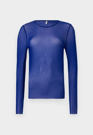 Duga bluza s dugim rukavima od prozirnog materijala ukrašena malim plavim draguljima, s okruglim izrezom i glatkim, blago teksturiranim materijalom.